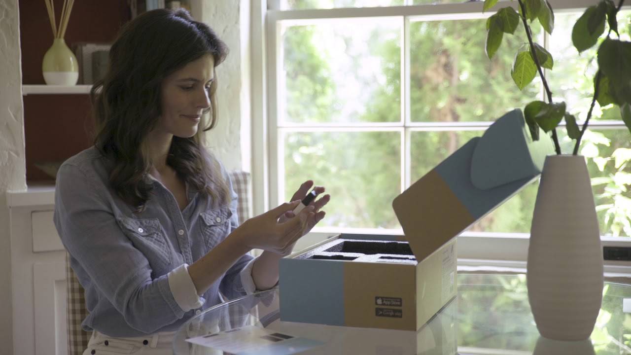 Woman at table opening abode home security package