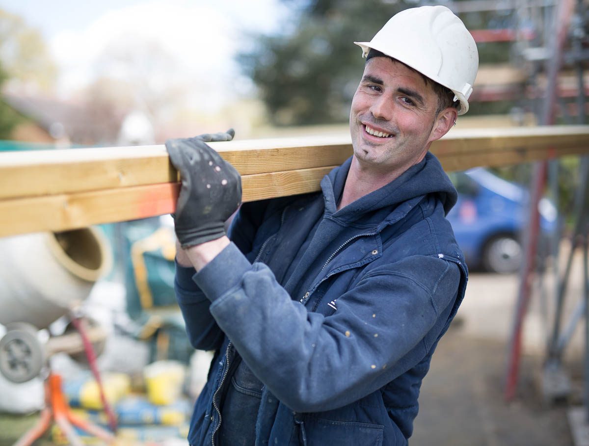 Trusted FMB builder carrying plank of wood and ready to start working on a new project.